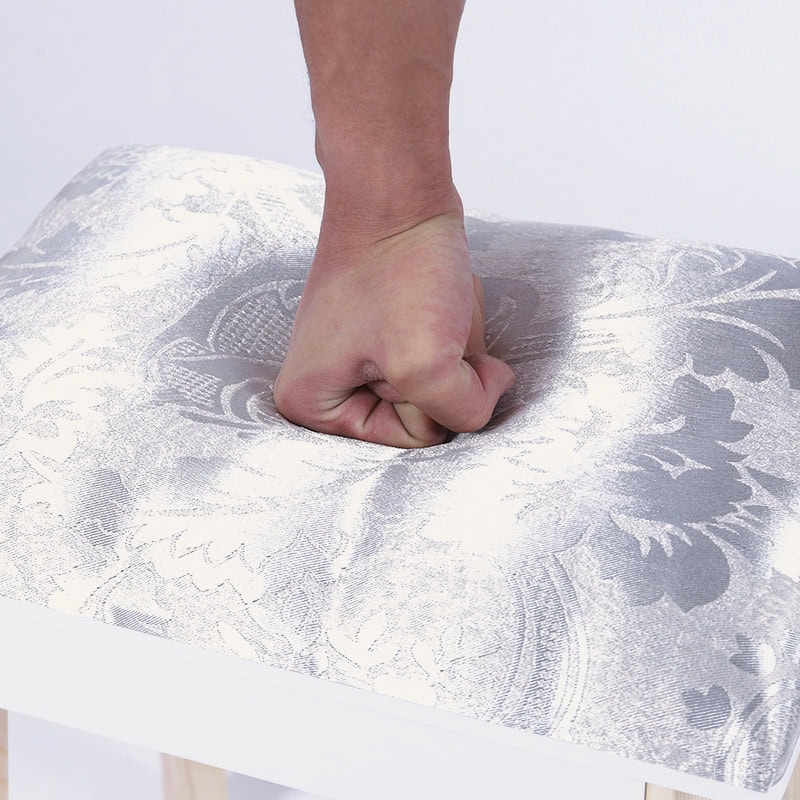 Person pressing on a patterned fabric surface with a clenched fist.