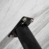 Close-up of a black metal table leg attached to a marble surface.