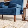Elegant blue velvet sofa with wooden legs in modern living room.