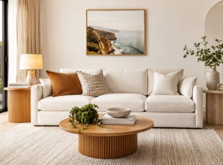 Modern living room with side tables, sofa, and coastal artwork.